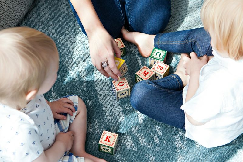 Fachkraft spielt aufmerksam mit zwei Kindern
